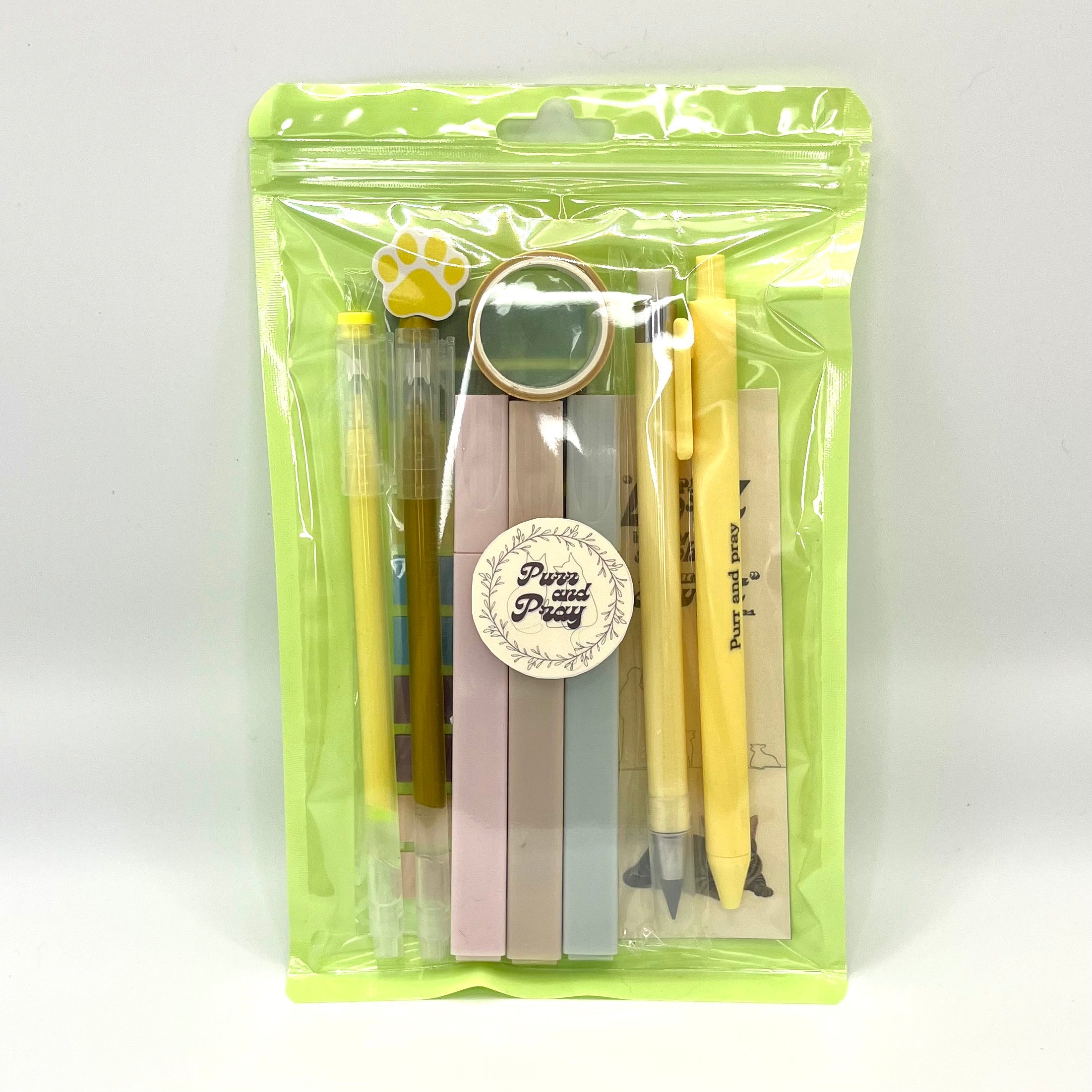 Stationery set packaged in a clear bag including pens, highlighters, sticky notes, washi tape, bookmark, and eraser for Christian journaling arranged neatly in yellow color palette.
