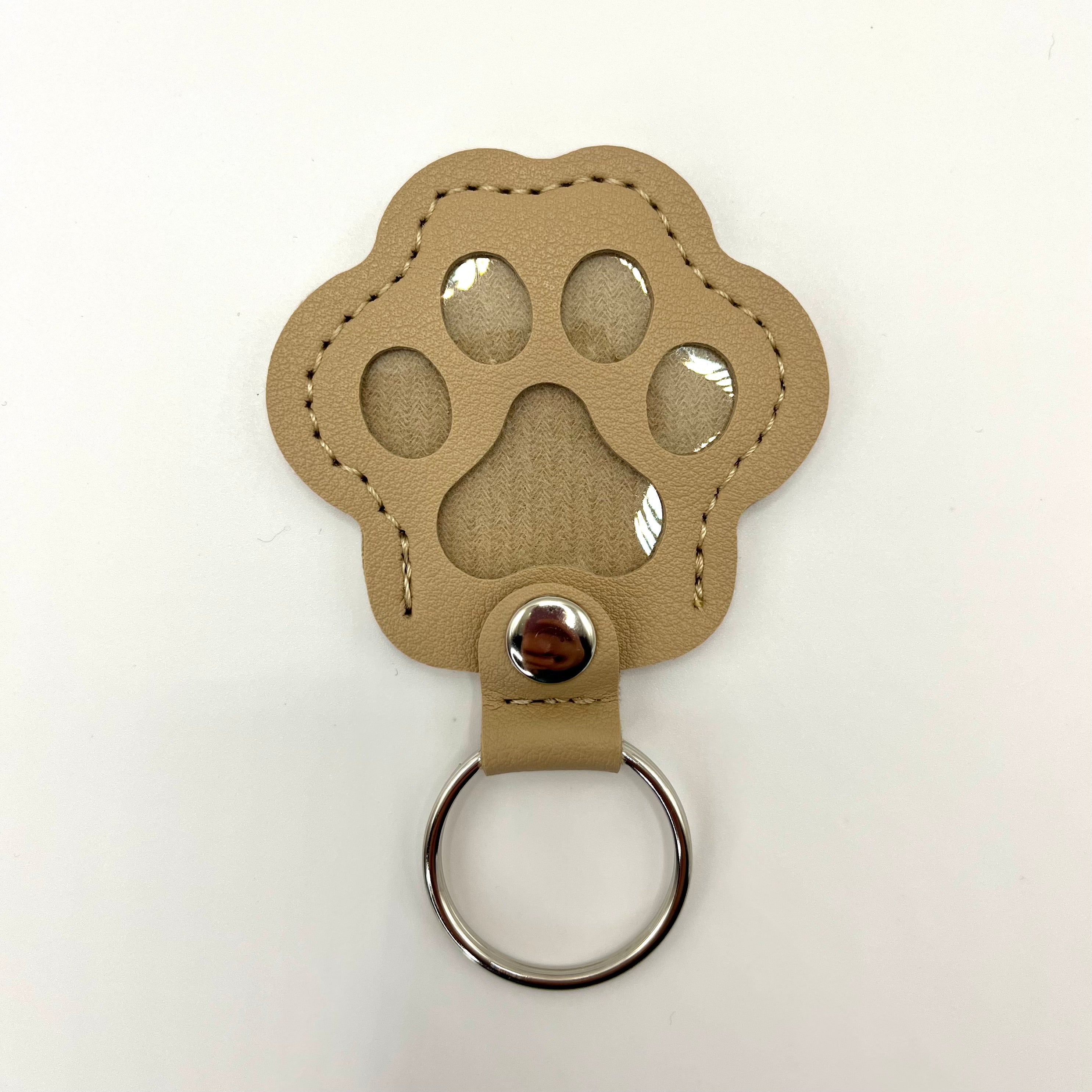 Beige faux leather paw-shaped keepsake keychain with metal ring – pet memorial gift.