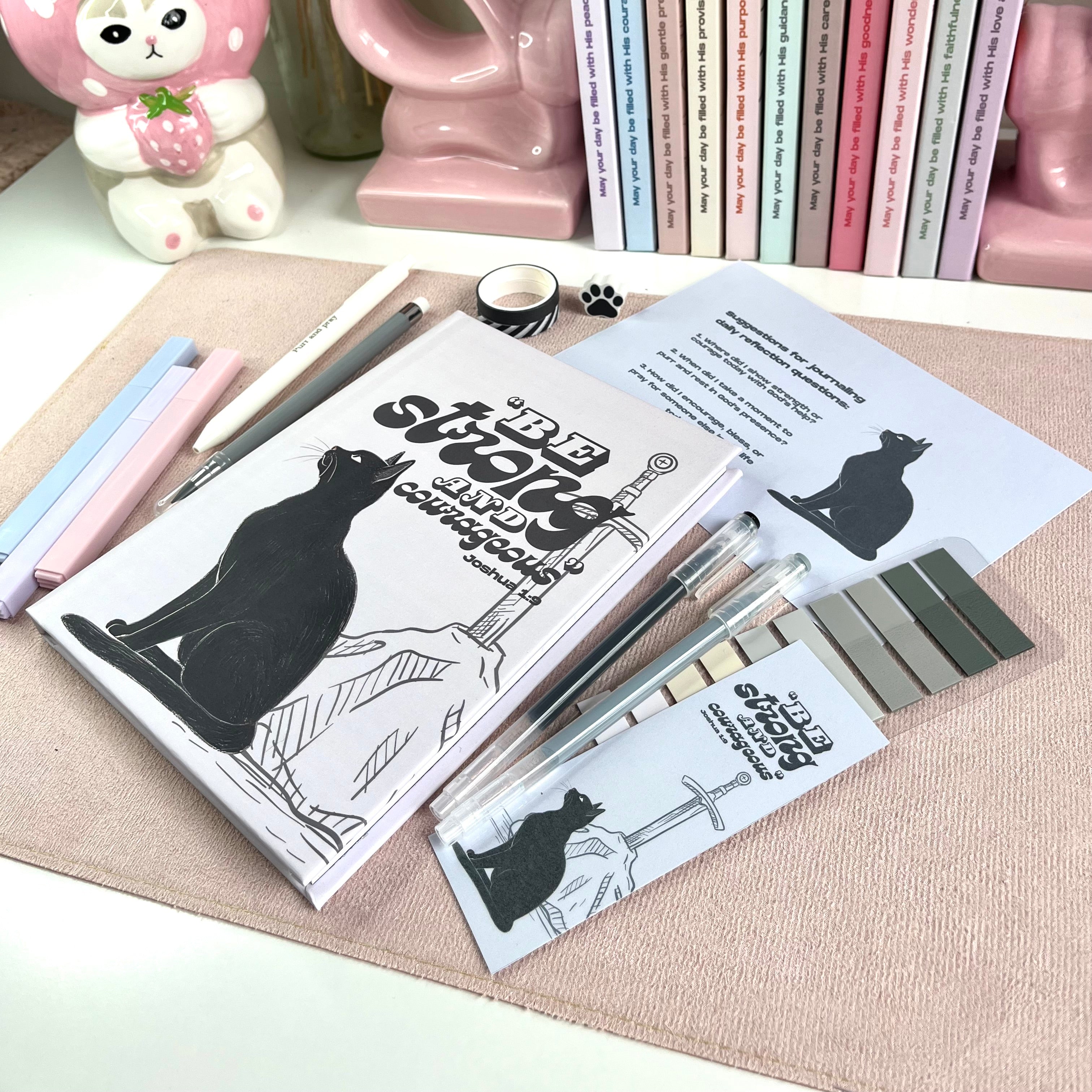 Cat-themed stationery set with books, pens, and a notebook on a textured surface.