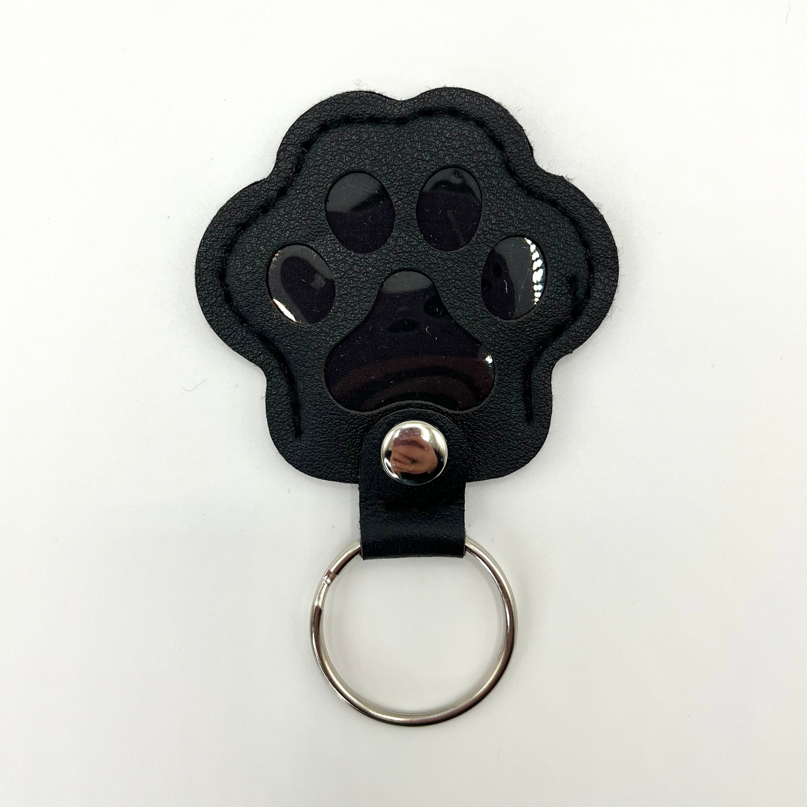 Black faux leather paw-shaped keepsake keychain with metal ring – pet memorial gift.