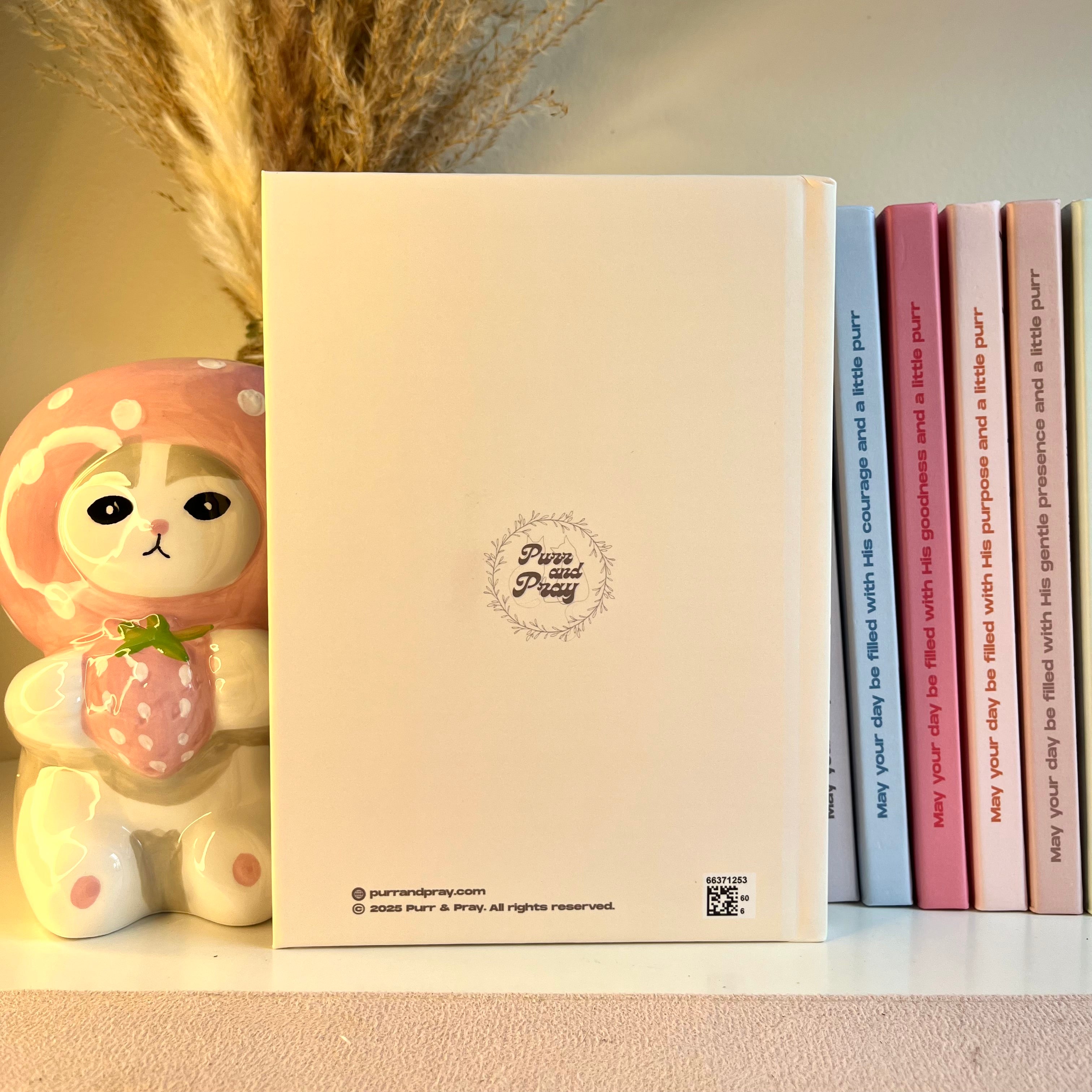 Yellow notebook with a cute character design on a shelf with books and a decorative item.