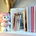 Packaged stationery items on a shelf with a decorative figure and books.