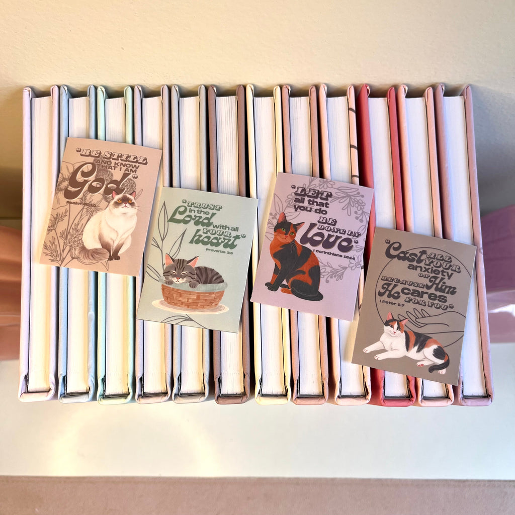 Stack of books with cat-themed stickers on a white surface