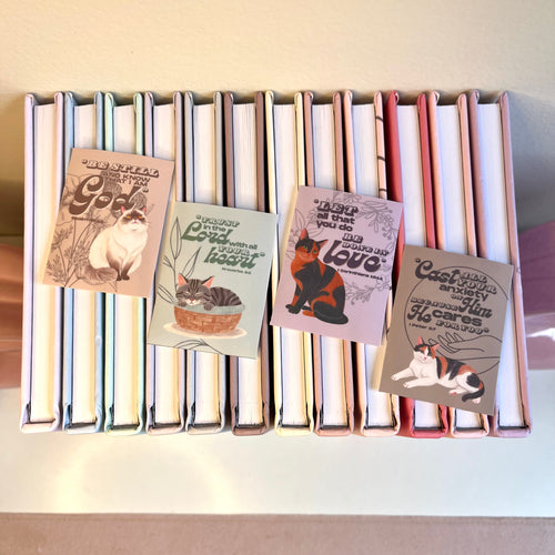 Stack of books with cat-themed stickers on a white surface
