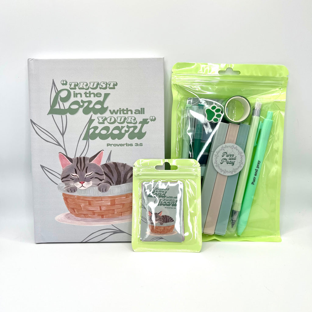 Packaged Christian gift set including a Bible verse journal with gray tabby cat artwork, stationery items in clear bags, and Scripture sticker pack.