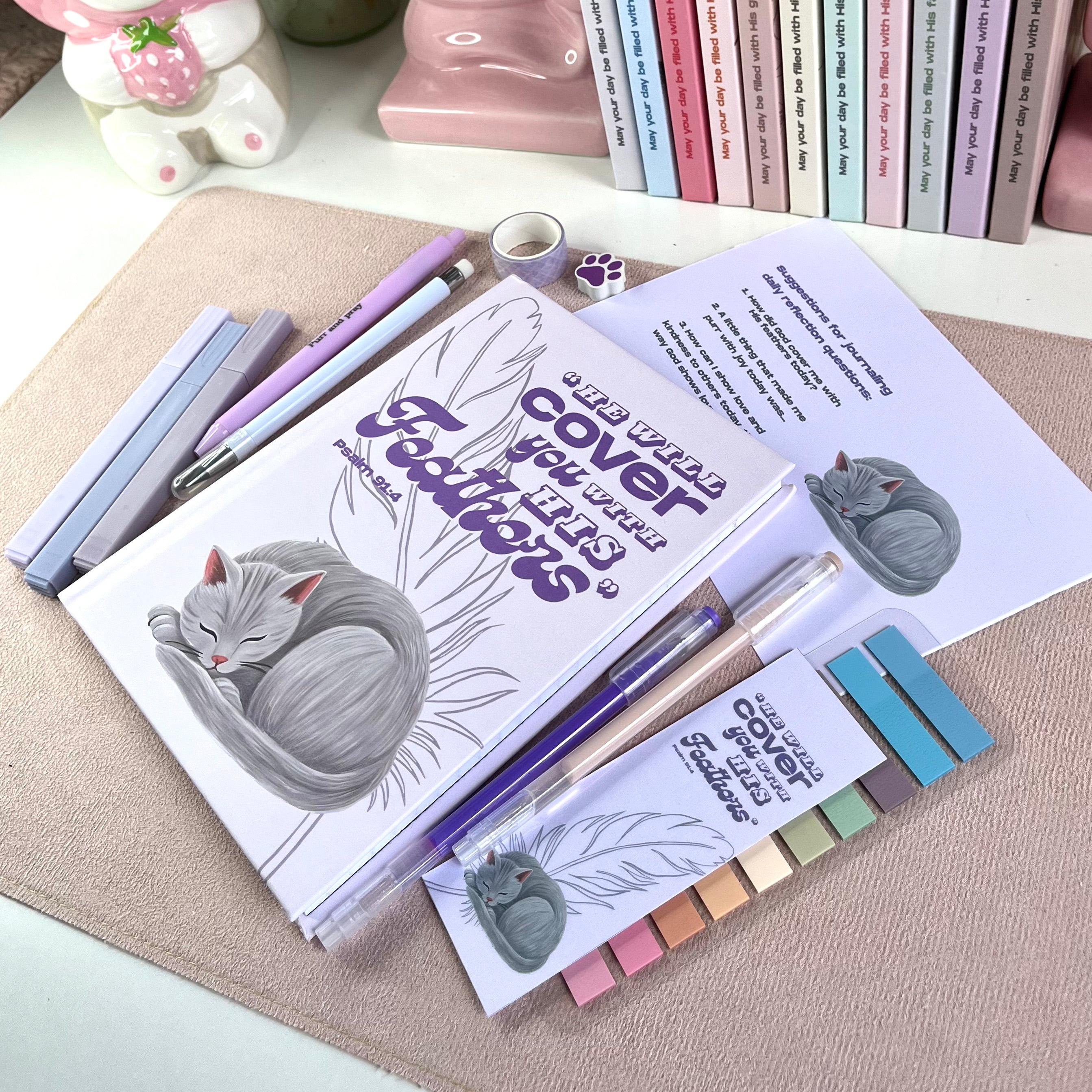 Stationery items including a notebook with gray cat illustrations, pens, and sticky notes on a textured surface.
