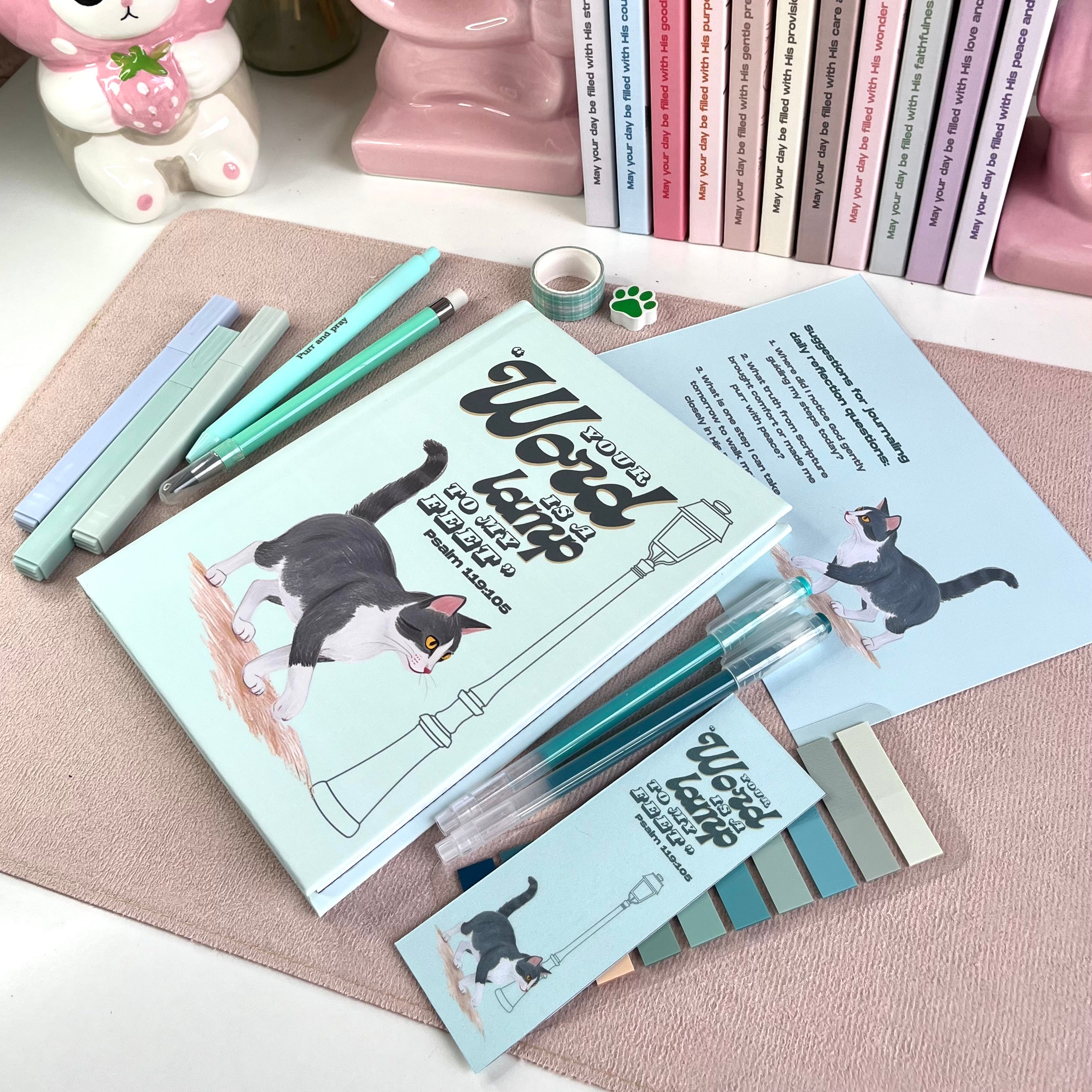 Stationery items including pens, a notebook, and stickers with cat illustrations on a textured surface.