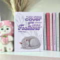 Lavender color book with a gray cat illustration and Bible verse text on a shelf with decorative items.