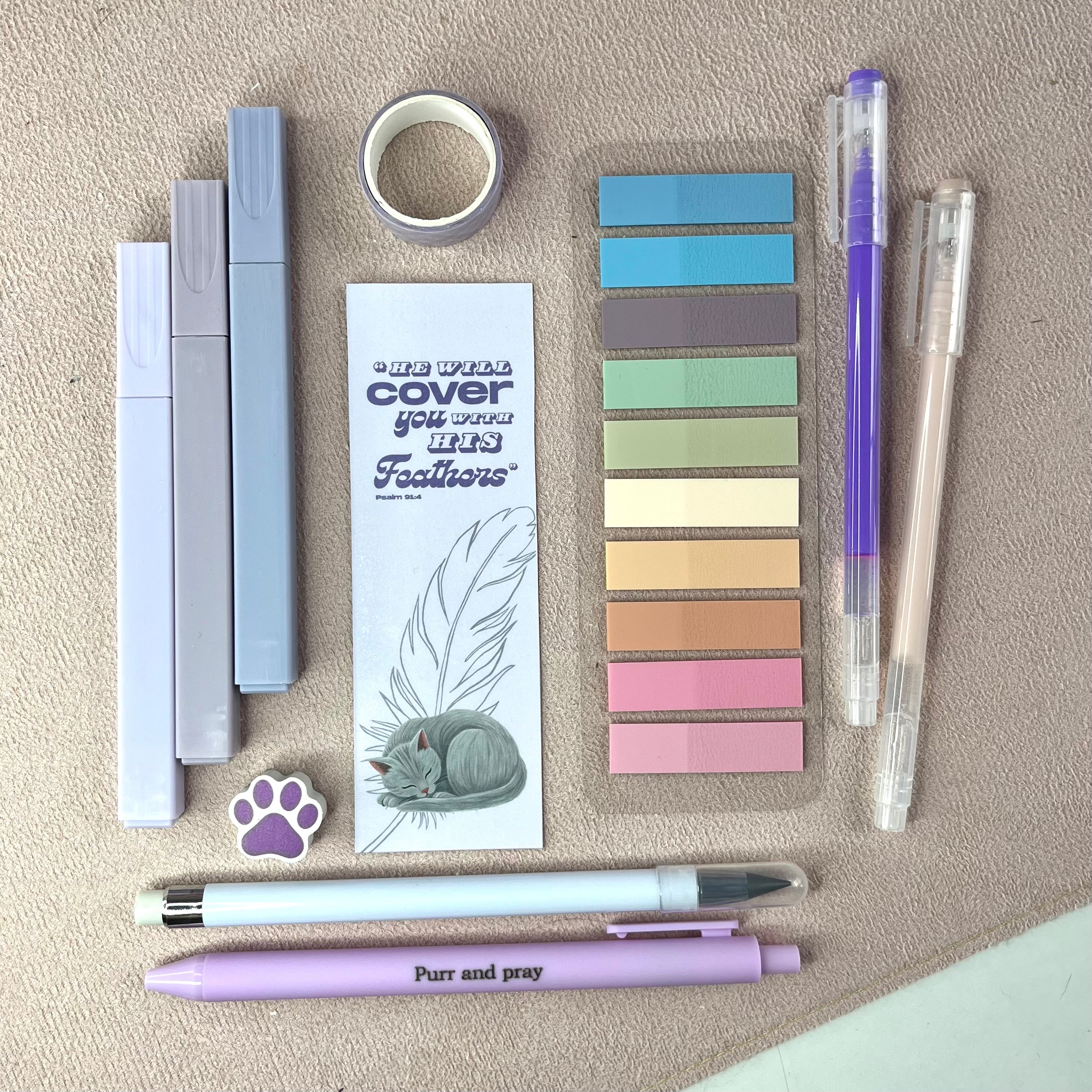 Collection of stationery items including pens, tape, and color swatches on a beige surface.
