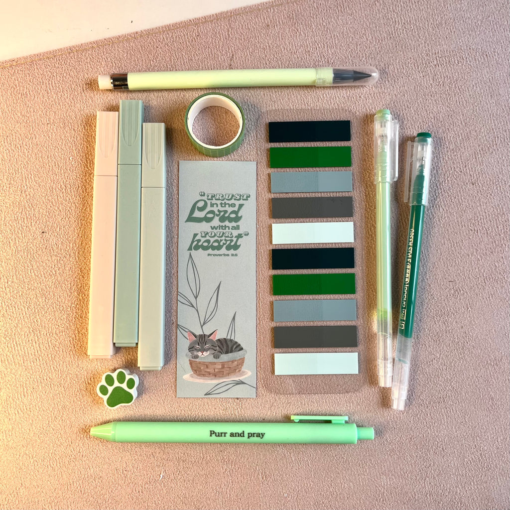 Green stationery items including pens and a gray tabby notebook.
