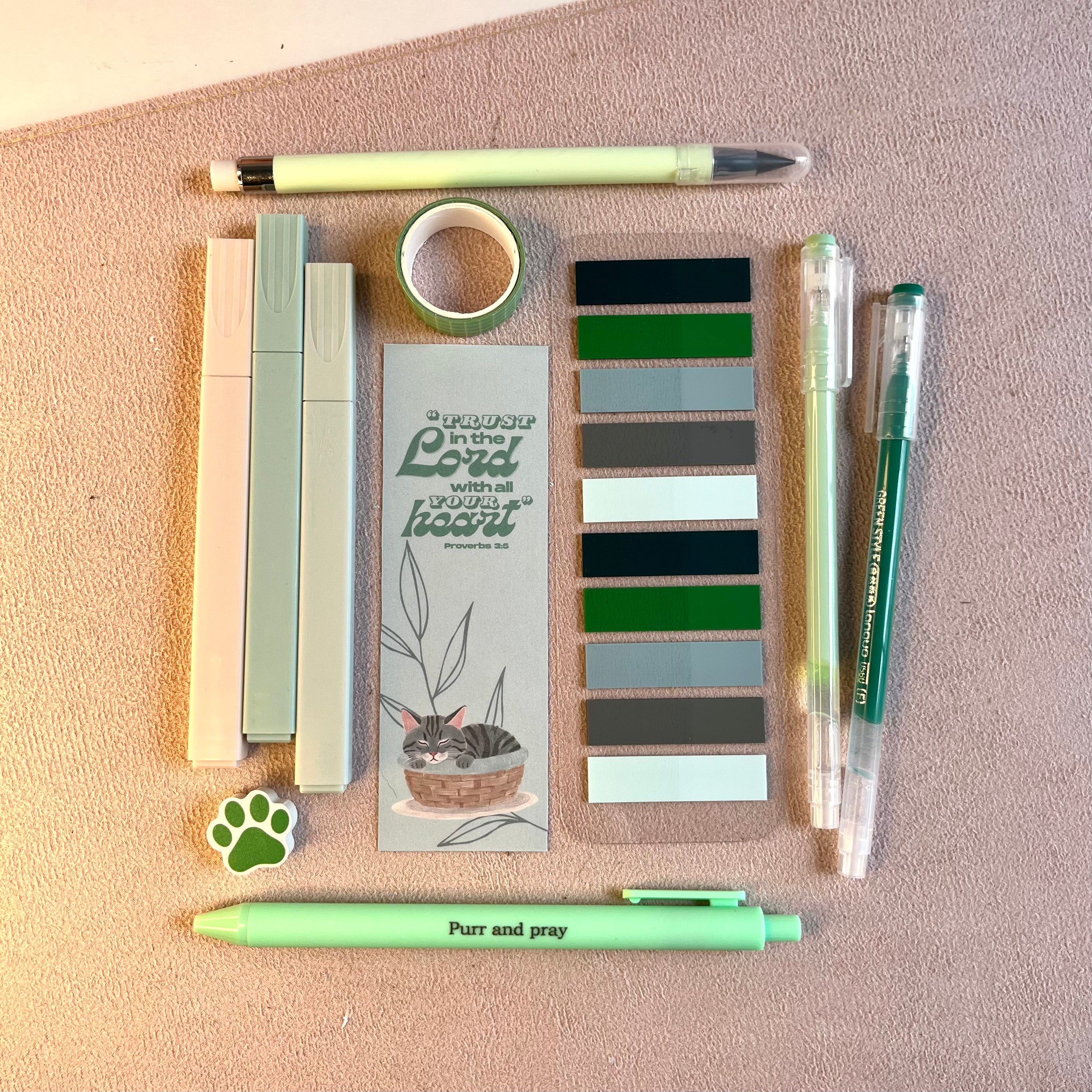 Green stationery items including pens and a gray tabby notebook.