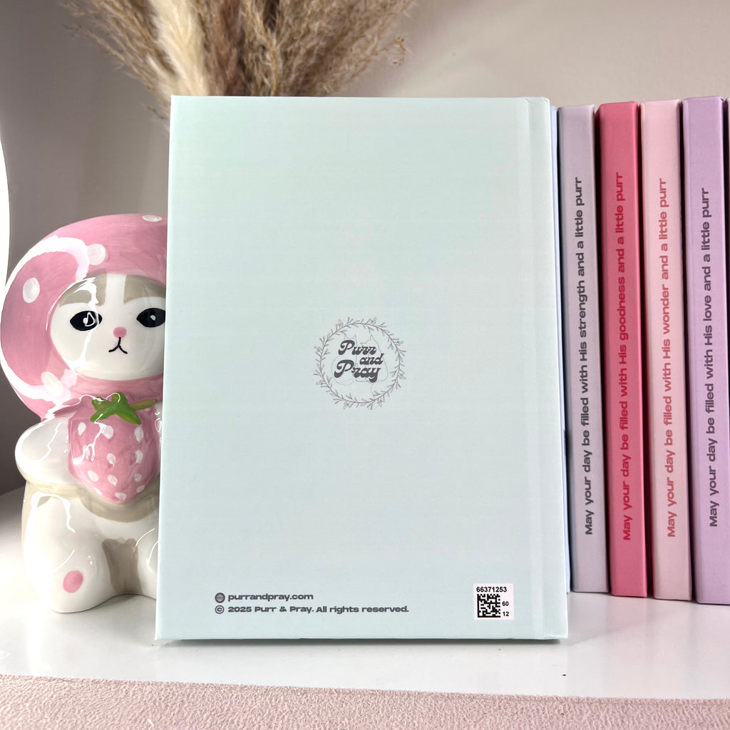 Notebook with a cute design on the cover, placed next to pink and purple books.