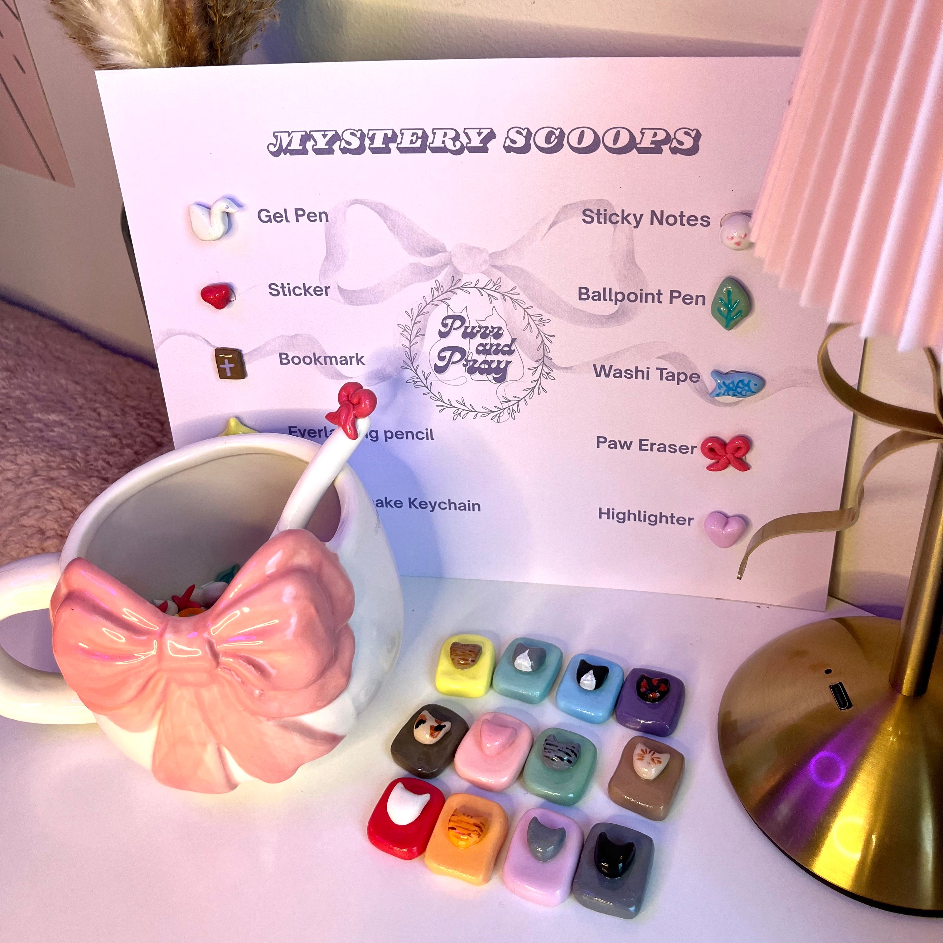 Set of stationery items including a mug with a spoon, paw-shaped erasers, and a display card for 'Purr and Pray' brand.