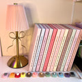 Set of books with colorful covers on a shelf next to a small lamp.