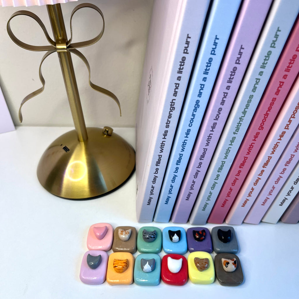 Row of books with personalized messages next to a gold lamp on a white surface