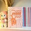 Orange notebook with an orange tabby cat illustration and motivational Bible quote, surrounded by decorative items.