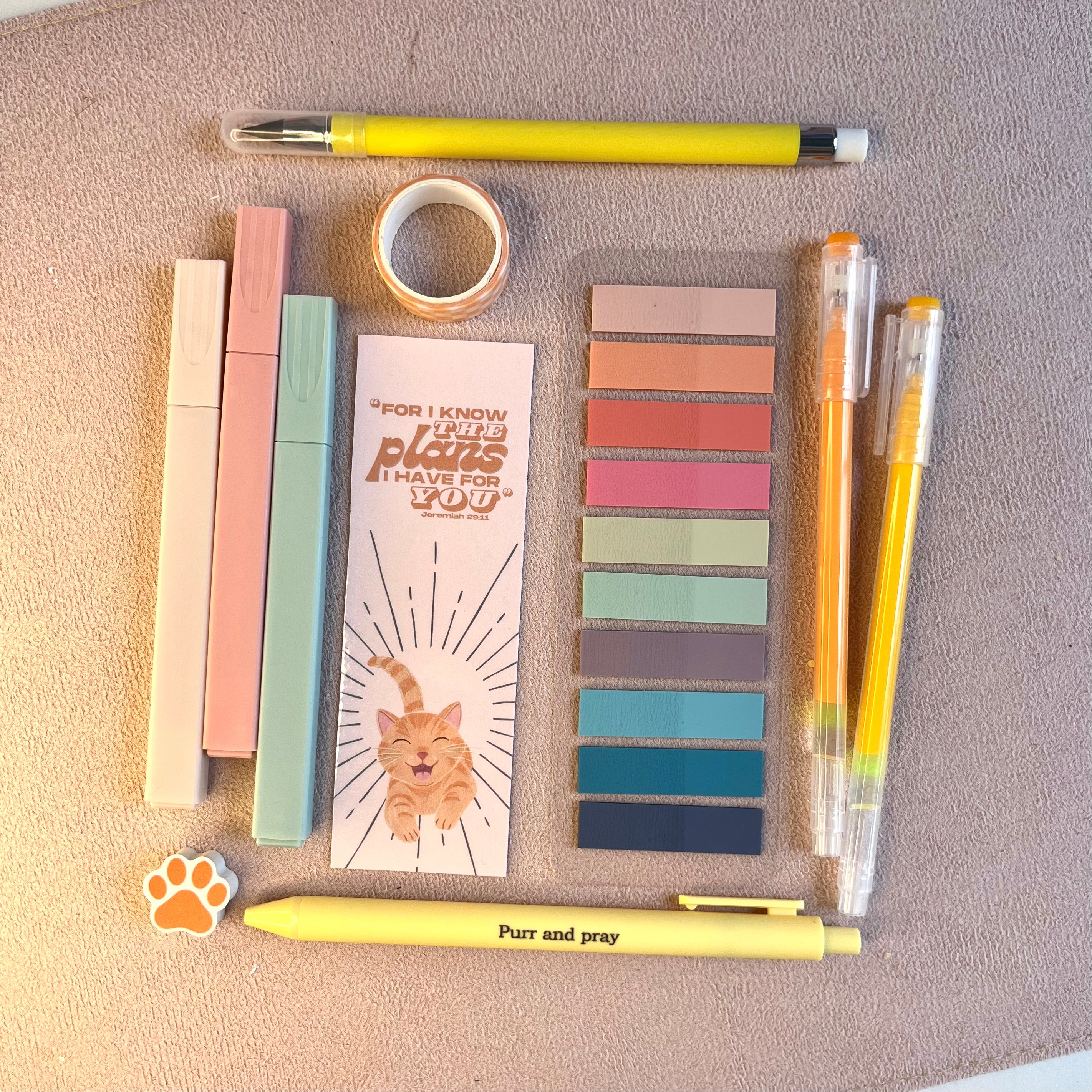 Collection of stationery items including pens, markers, and a bookmark on a textured surface.