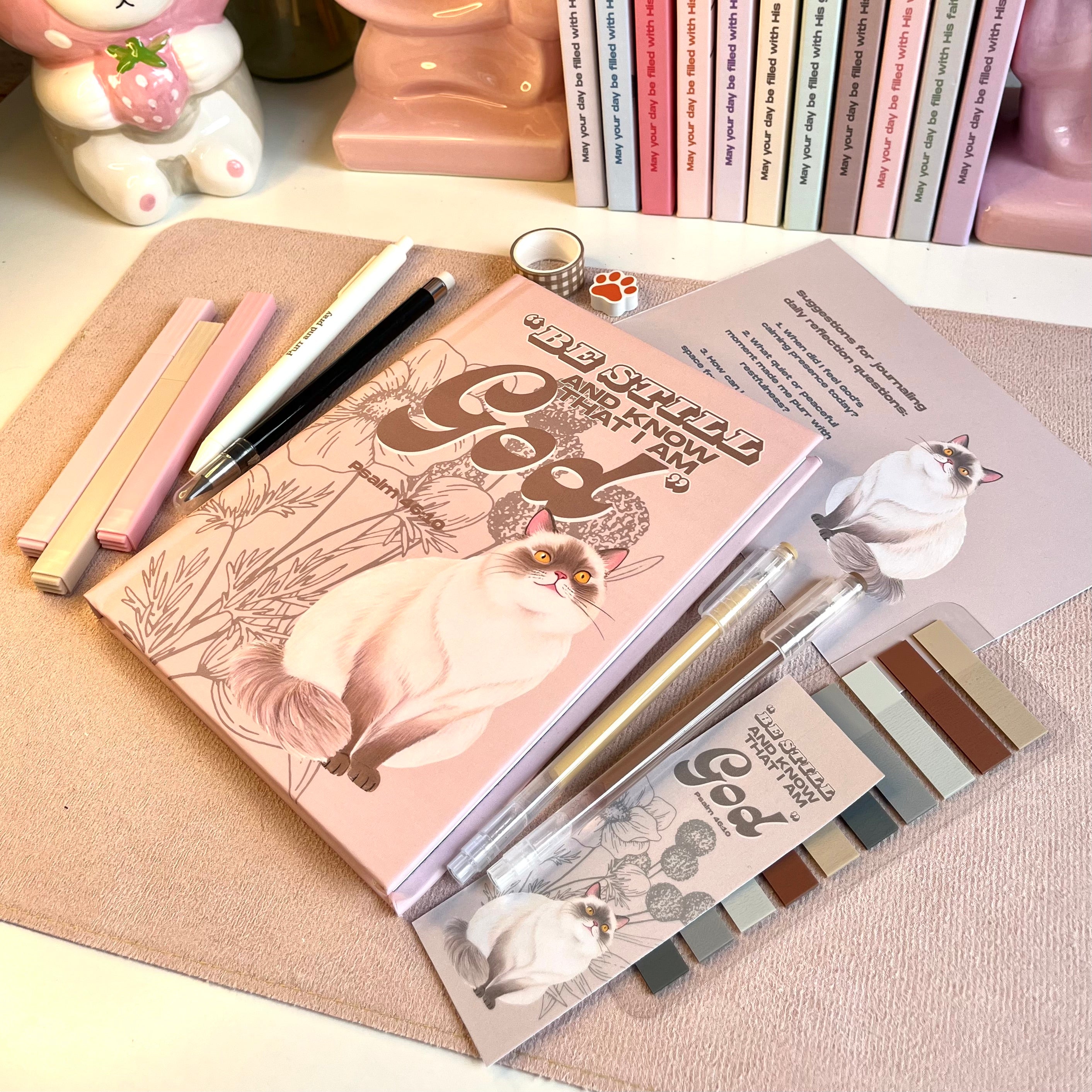 Cat-themed stationery items including notebooks, pens, and stickers on a textured surface.