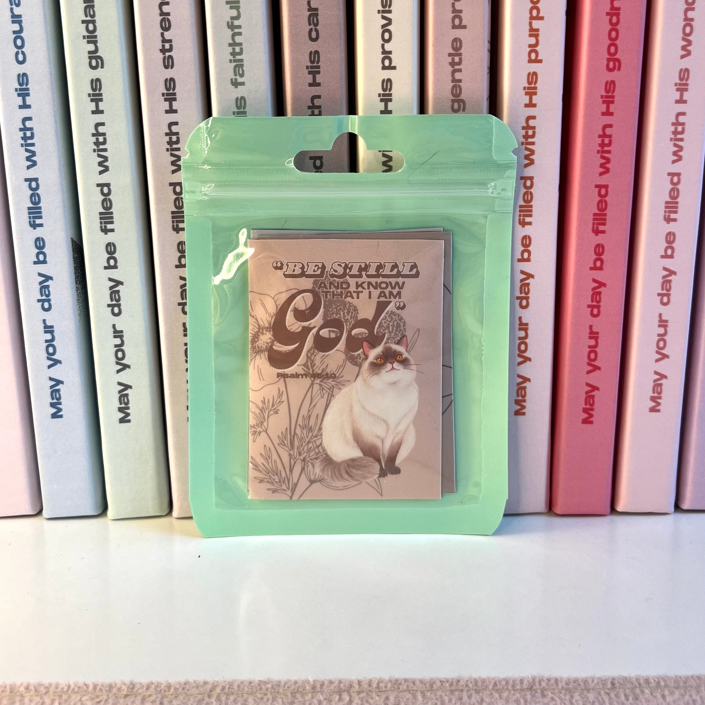 Packaged stickers with a cat illustration on a shelf with books in the background
