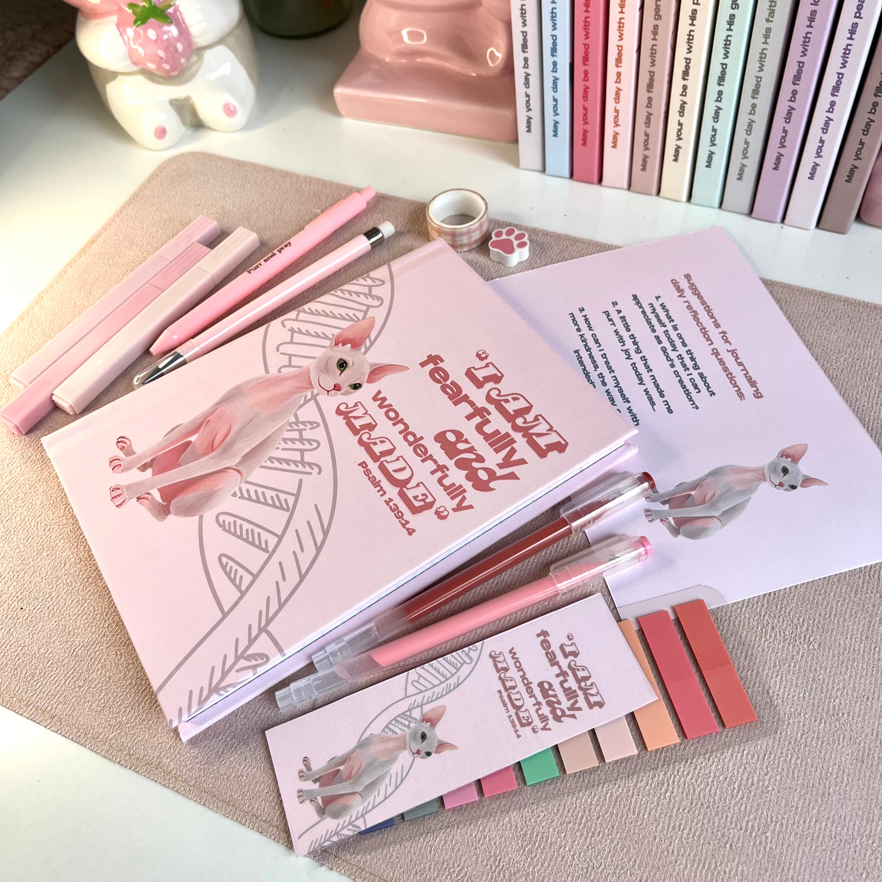 Stationery set with pink pens, notebooks, and stationery items on a textured surface.