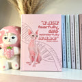 Pink notebook with a sphynx cat illustration and  Bible verse text, next to a decorative figurine and books.