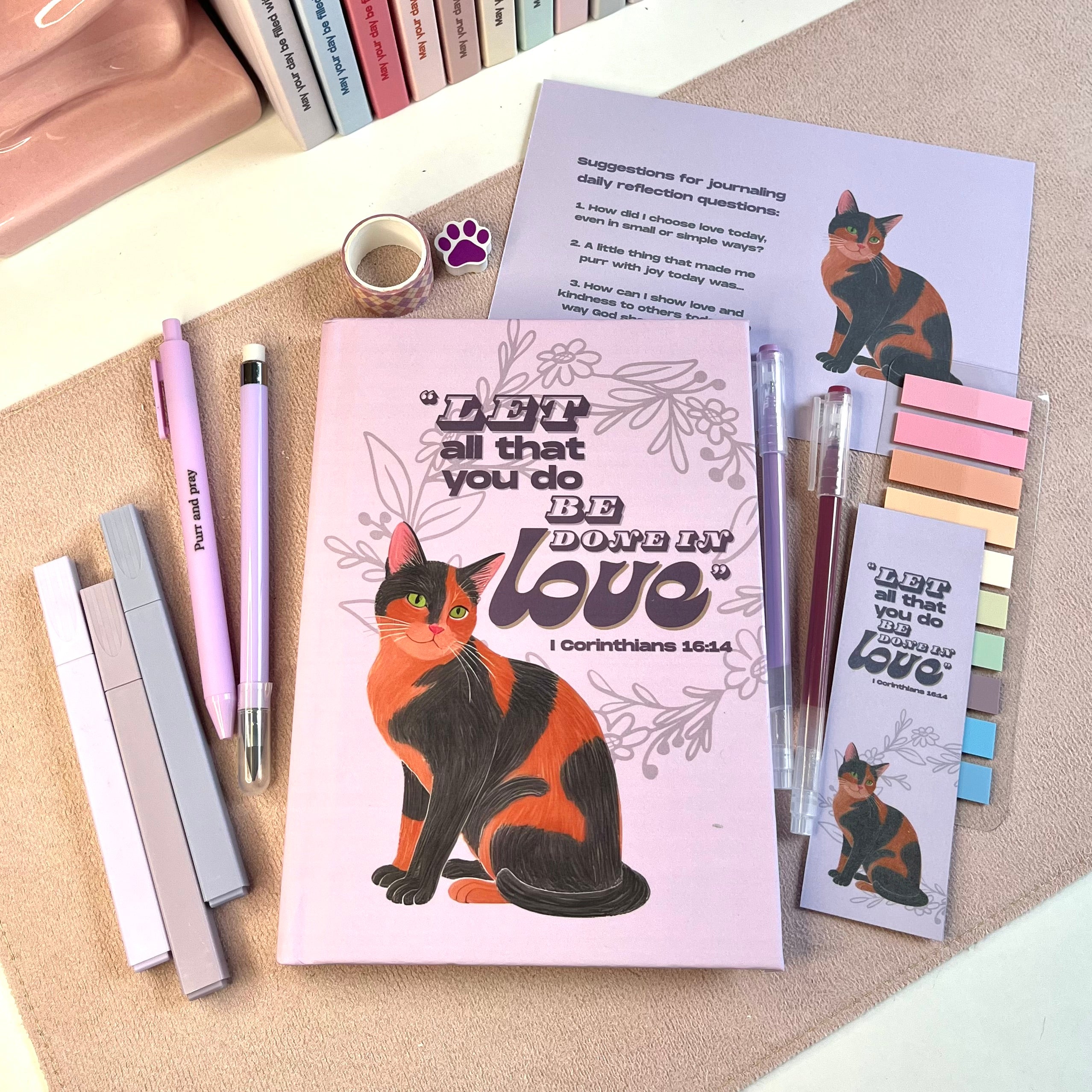 Cat-themed stationery items including a notebook, pens, and post-it notes on a textured surface.