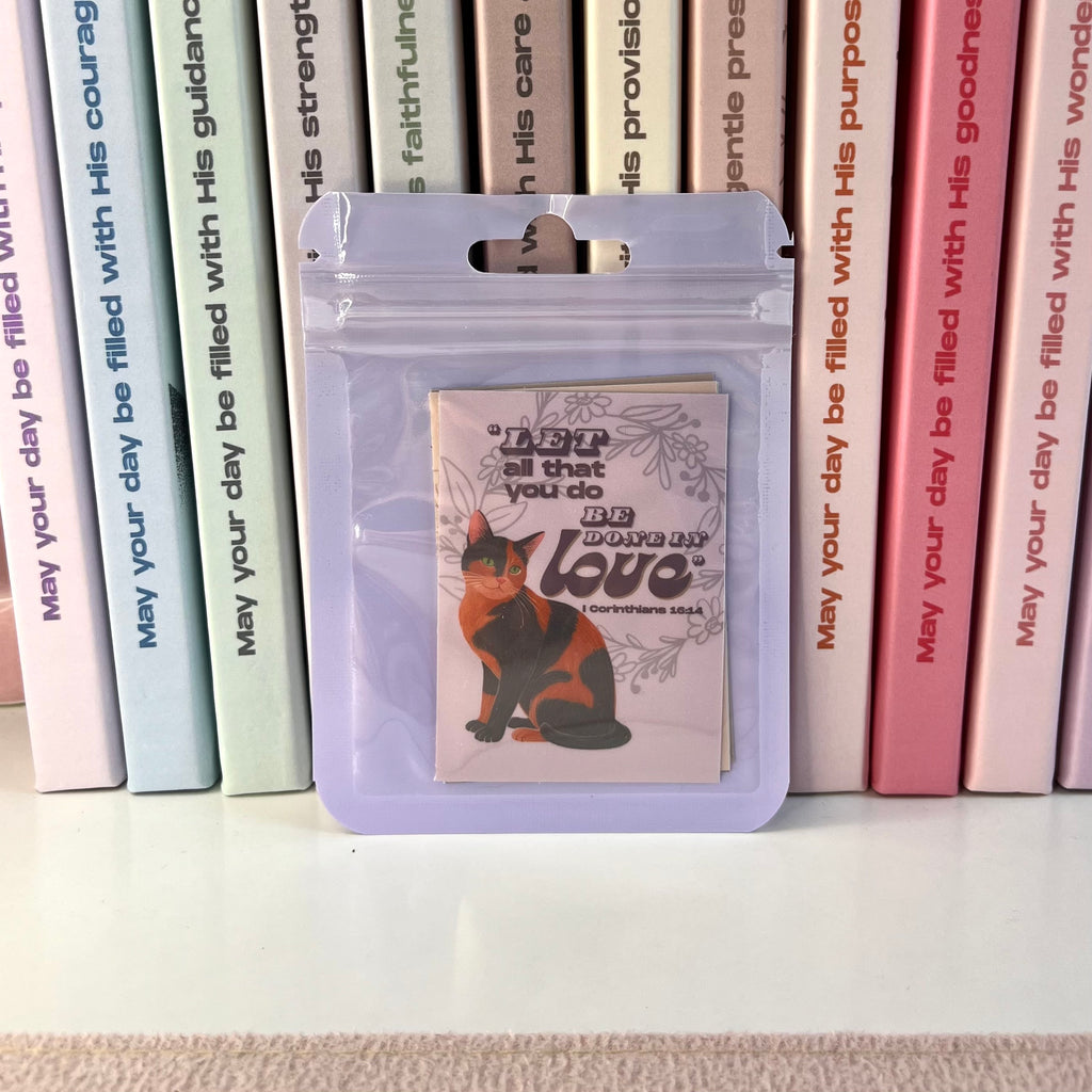 Purple pouch with a cat illustration and text, placed among books with motivational messages.