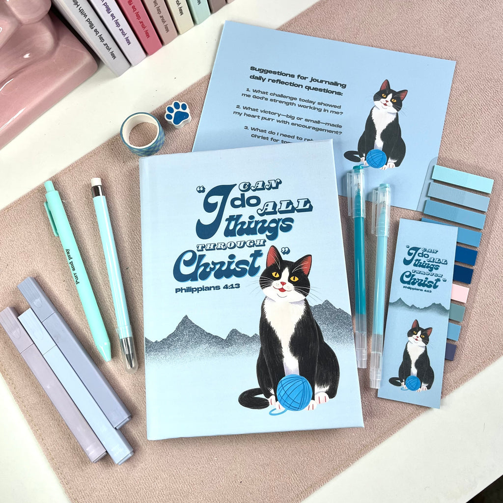 Stationery items with tuxedo cat illustrations and motivational text on a textured surface
