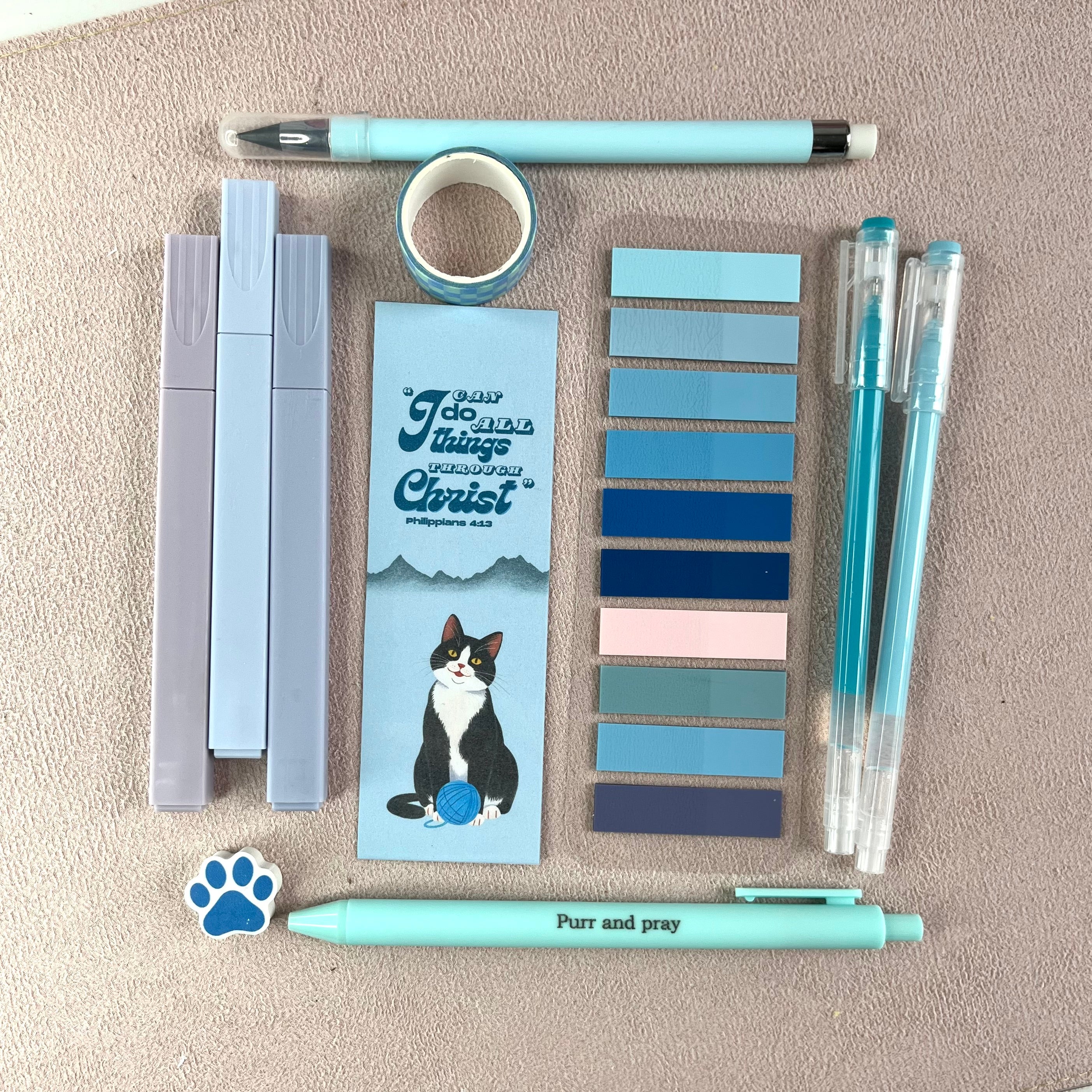 Collection of blue stationery items including pens, tape, and bookmarks on a textured surface