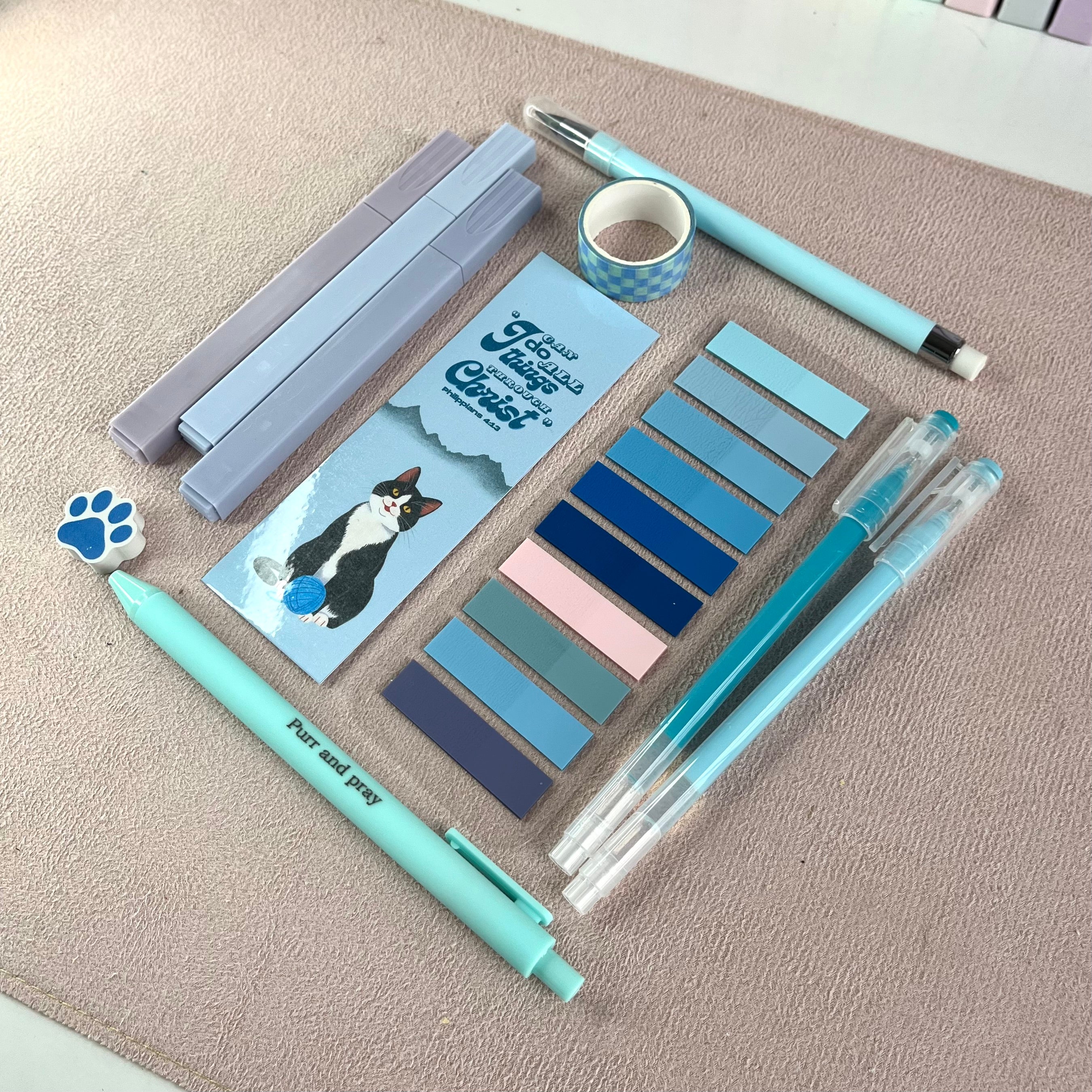 Blue stationery items including pens, markers, and stickers on a textured surface