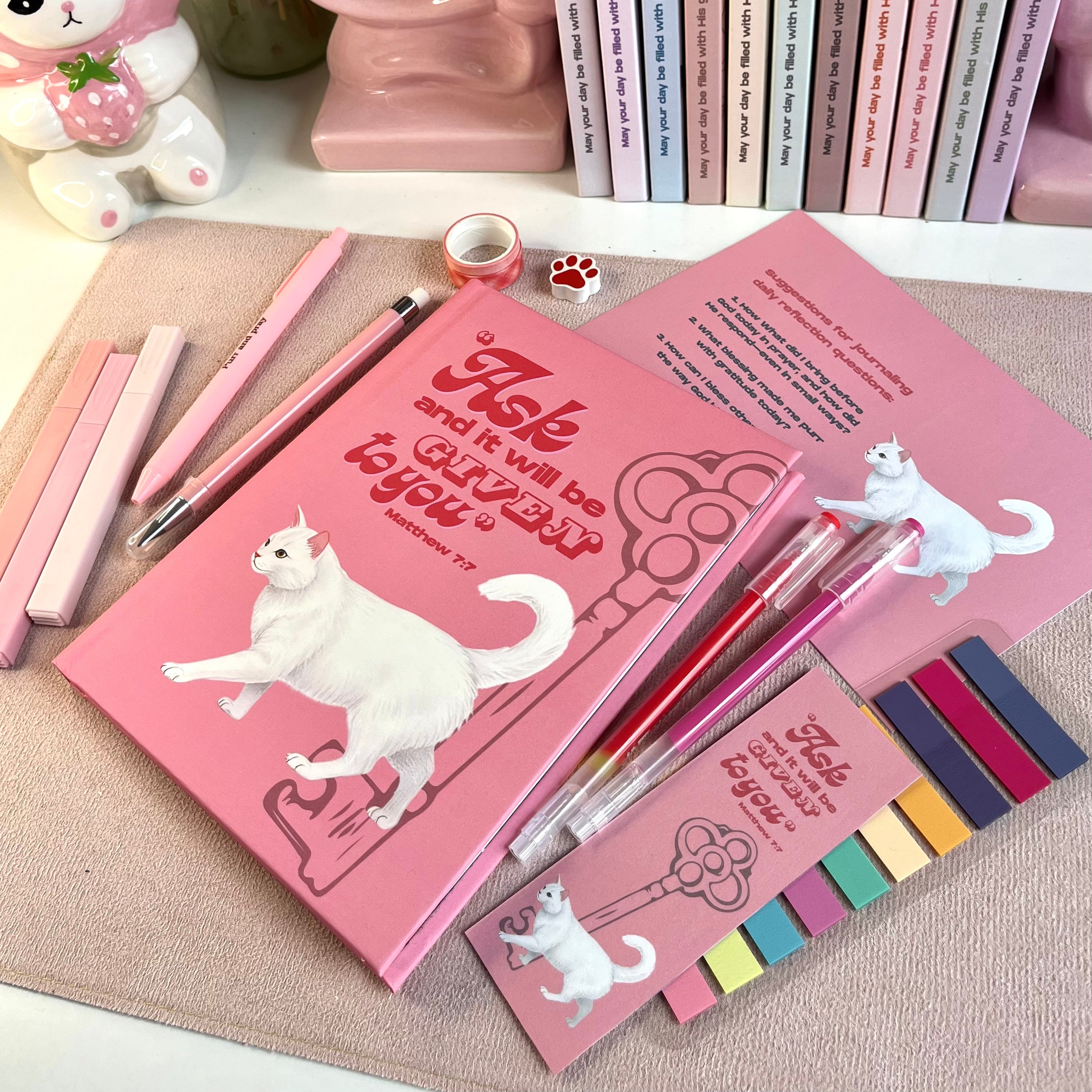 Pink stationery set with white cat illustrations on a textured surface