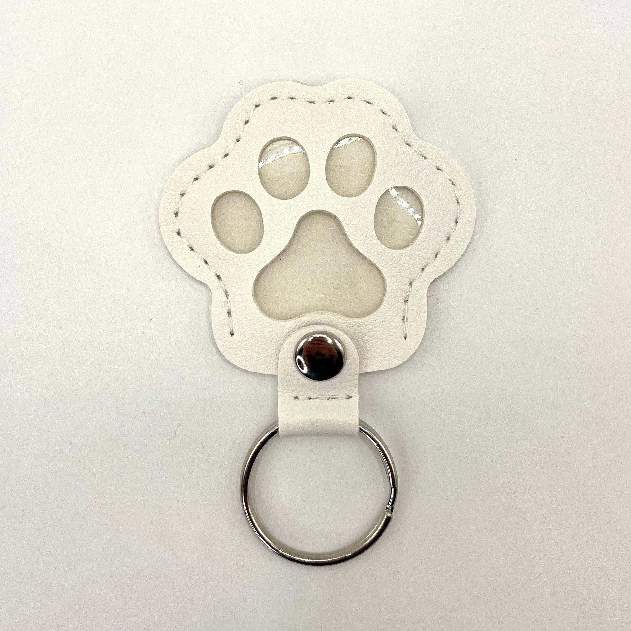 White faux leather paw-shaped keepsake keychain with metal ring – pet memorial gift.