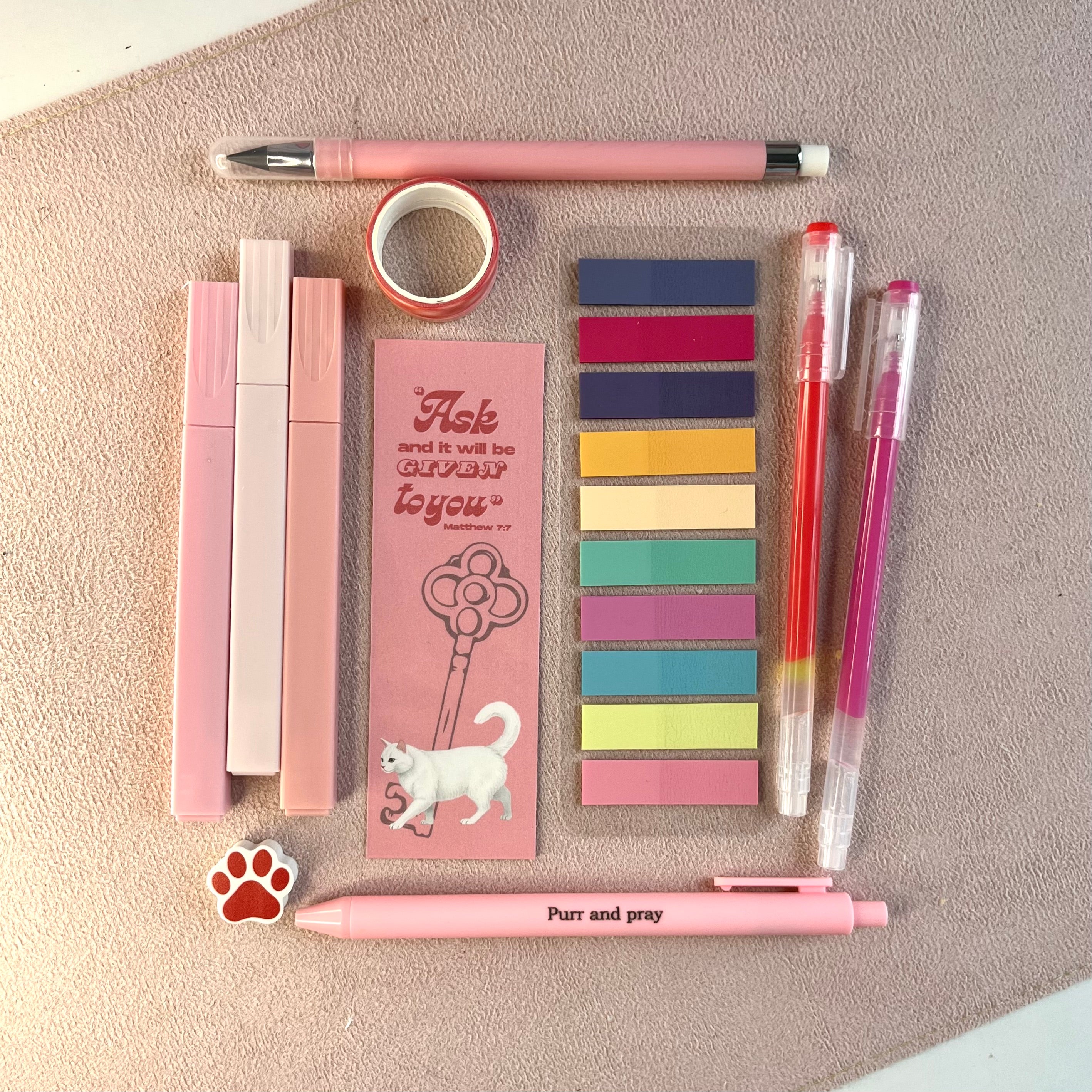 Stationery items including pens, sticky notes, and a bookmark on a textured surface
