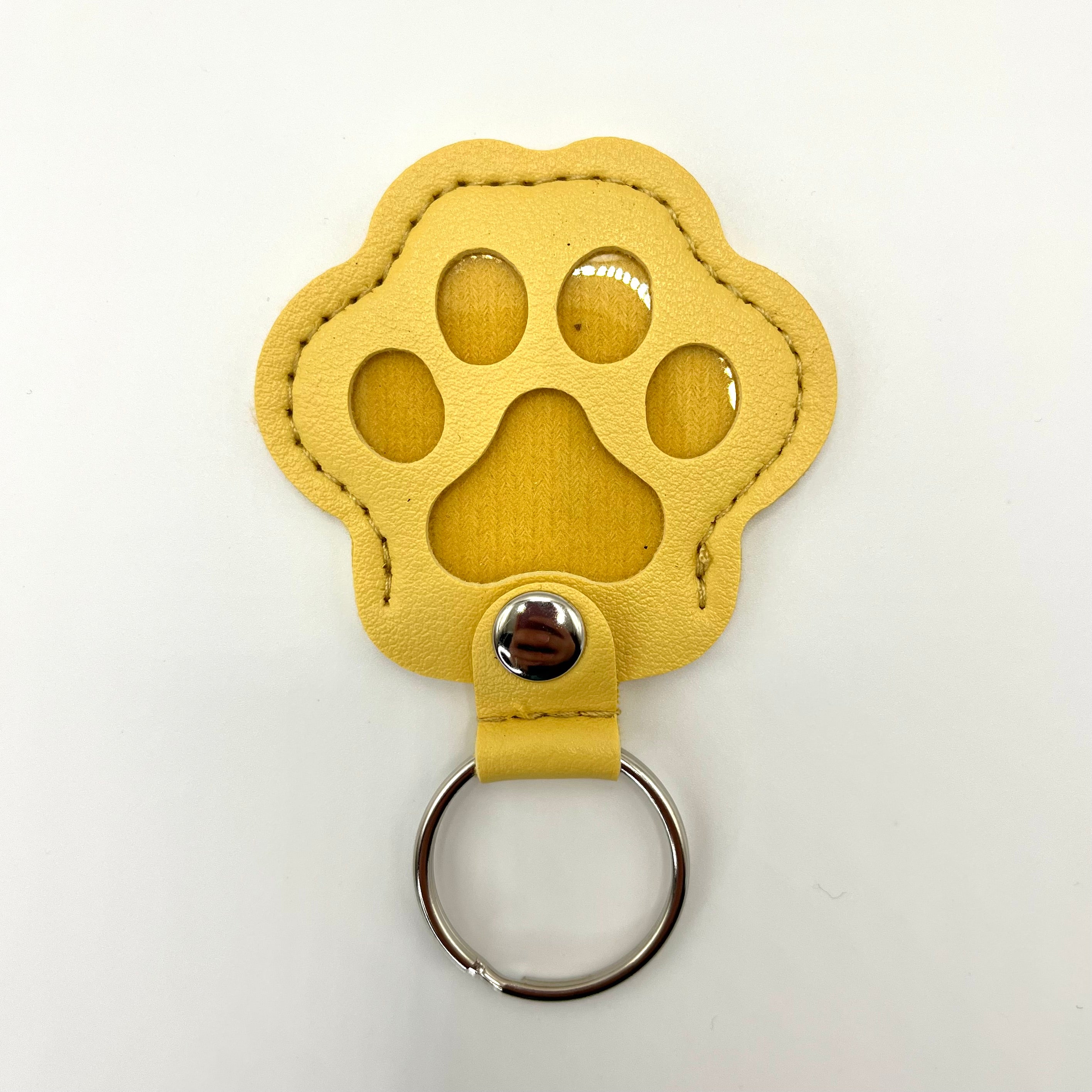 Yellow faux leather paw-shaped keepsake keychain with metal ring – pet memorial gift.